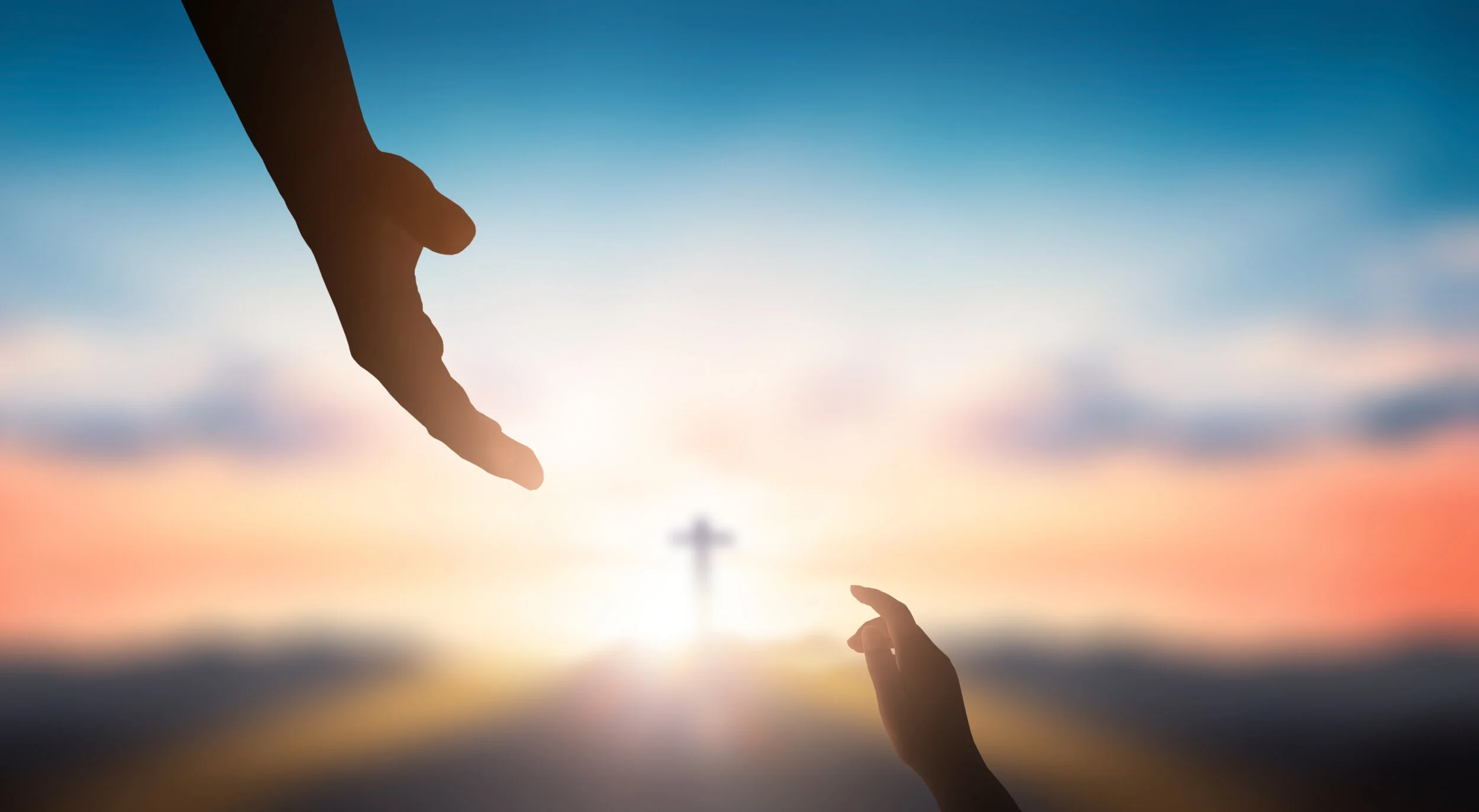 A child holding a Bible beneath a cross at sunset